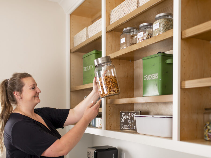 Shelby Brandon 2B Organized Denver franchise owner and professional organizer adds a decanted jar of pretzels to a shelf.